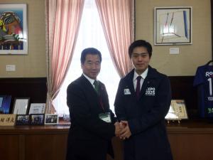 町長と吉村洋文大阪府知事が横並びでお互いの両手を重ねて握手をしている写真