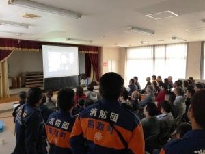 五門地区自主防災組織委員会訓練でスクリーンに映された防災ビデオを見ている住民の皆さんや消防団の方々の写真