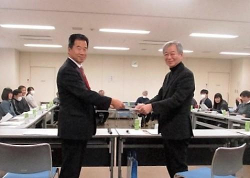 町長と山本健慈会長が体をお互い向き合わせて並んでいて、顔は正面をみてほほ笑んでいる写真