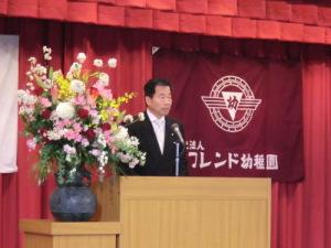 花が飾られた演台に立っている町長の写真