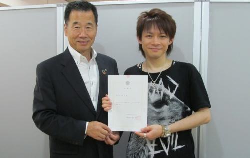 委嘱状を手に持ち笑顔で並ぶ喜多修平さんと町長の写真