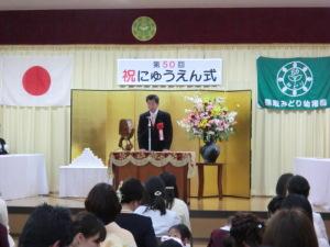 入園式でリボン記章を付けた町長が演台に立っている写真