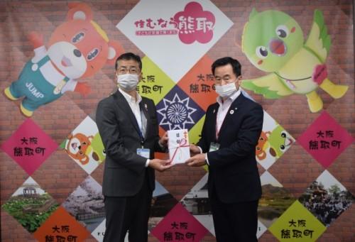 目録と書かれた祝儀袋を町長とスーツ姿の男性が二人で持っている記念写真
