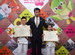 町長を真ん中に町民スポーツ賞授与された奈木君と井上さんが賞状を持ち笑顔で記念撮影している写真
