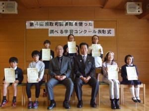 熊取町図書館を使った調べる学習コンクールで表彰された人達が賞状を持ち町長と並んで写した集合写真