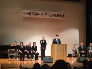 演台に立ち祝辞を述べる町長と、その横で手話をしている女性の写真