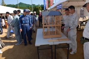 テントの前に展示された木材でできた建物を見ている参加者の人達の写真