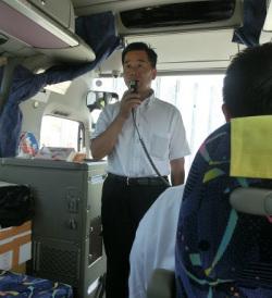 バスの中で、マイクを持って話をしている町長の写真
