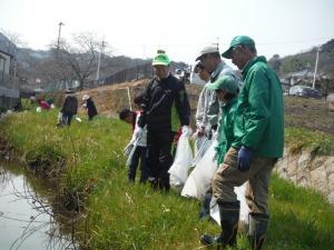 見出川で、ごみ袋をもってごみを集める町長と、参加者の写真