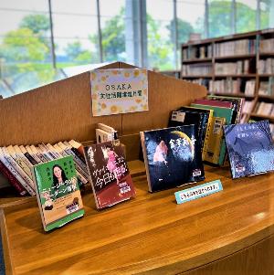 「OSAKA女性活躍推進月間」の表示の下に本棚に並べられている書籍とテーブルに並べられているの本を紹介している特集コーナーの写真